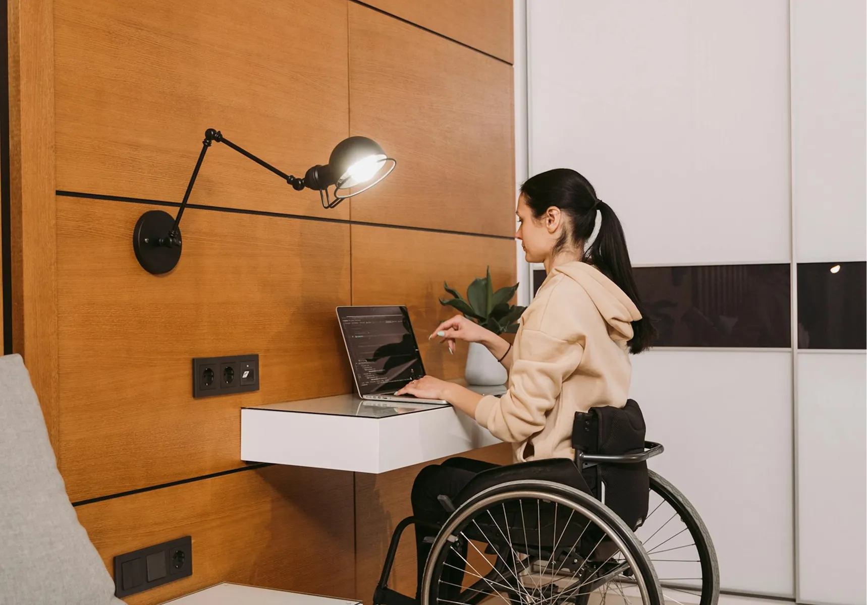 A woman in a wheelchair working independently at her desk
